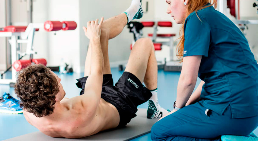 Instructor guiding a resident through a pilates movement